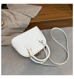 Detail of white quilted shell bag showing Chevron stitching and gold zipper hardware