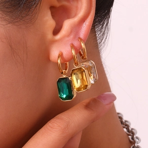 Close-up of gold-plated hoop earrings featuring rectangular green and yellow zircons