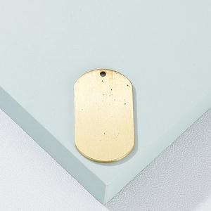 Minimalist gold titanium steel dog tag pendant displayed on a light blue geometric stand