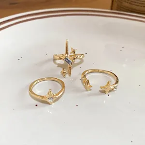 Three-piece set of gold starburst rings with zircon stones on a white ceramic plate