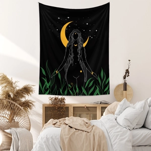 Detail of bohemian black and gold tapestry with moon silhouette above a bed