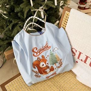 Detailed squirrel embroidery on a light blue nylon tote bag with woven cord handles