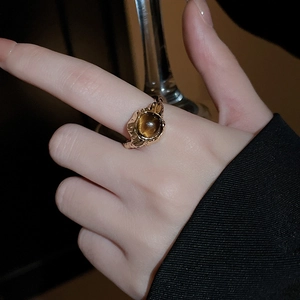 Close-up of gold-plated ring with amber gemstone and textured lava metal design