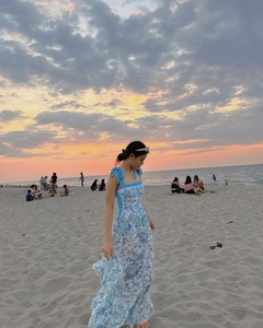 Detail of blue floral dress with shoulder bow ties at sunset beach vacation setting