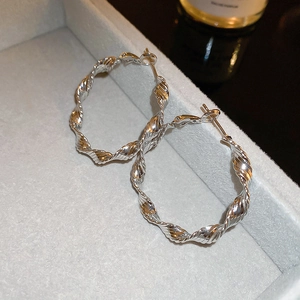 Detail of silver twisted hoop earrings with diamond accents on a grey jewelry box display