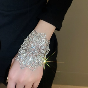 Makroaufnahme eines silbernen funkelnden Blumenarmbandes mit Diamanten an einer Hand