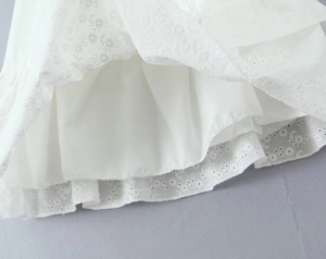 Detailansicht der weißen floralen Ösenstickerei und der Rüschen am Baumwollkleid