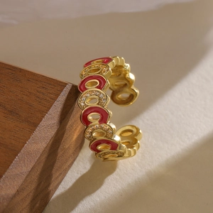 Macro detail of gold plated enamel ring with red drip oil and zircon on dark wood