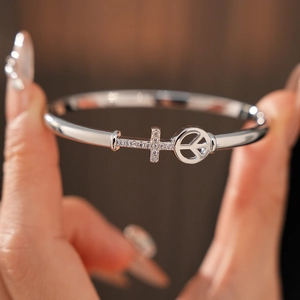 Close-up of gold plated arrow cross bangle with micro-paved zircon details on wrist