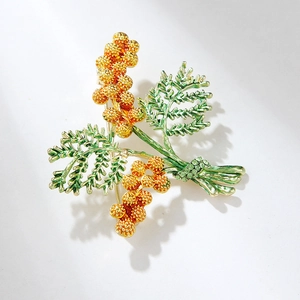 Detail of pine cone brooch with green leaves and gold petals featuring sparkling crystals