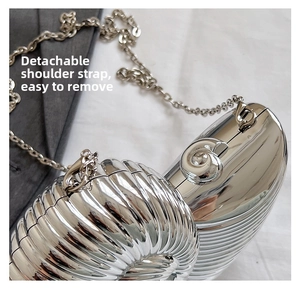 Detail of silver snail-shaped evening bag featuring a detachable metal chain strap