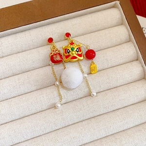 Lion bow earrings with white fur balls and red beads displayed in a jewelry box