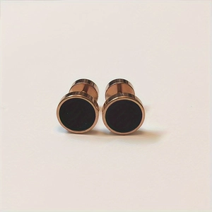 Close-up of circular rose gold stainless steel stud earrings with black enamel inlay