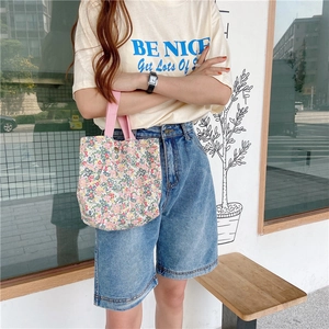 Floral canvas mini tote bag with pink straps shown held by a model in casual street style