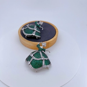 Exquisite ballerina brooch featuring green crystals and silver finish on a wooden stand
