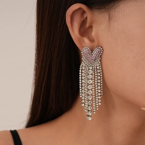 Macro view of long silver tassel earrings with pink heart and sparkling crystals