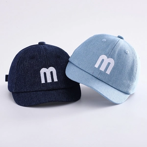 Detail of infant soft brim denim baseball caps in dark and light blue with letter embroidery