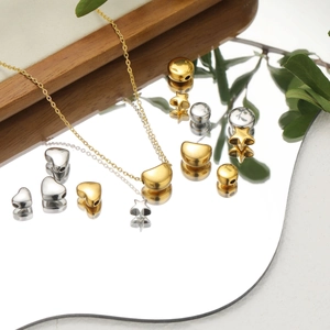 Golden and silver geometric heart and star charms for DIY jewelry on a mirror surface