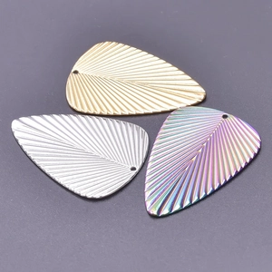 Macro detail of leaf-shaped stainless steel charms in gold, silver, and rainbow finishes
