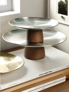 Detail of a two-tier round tray with silver metal plates and brown wood pillar