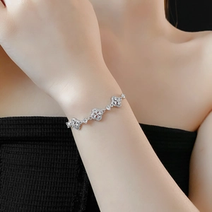 Detail of silver clover bracelet with sparkling zircons on female wrist for elegance