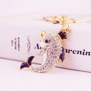 Golden dolphin keychain with sparkling rhinestones and crown detail on a book background