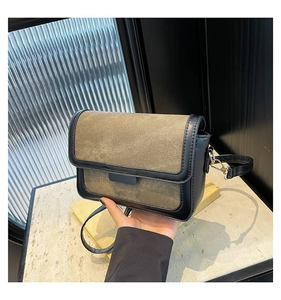 Detail of khaki canvas and black leather shoulder bag with metallic buckle and strap