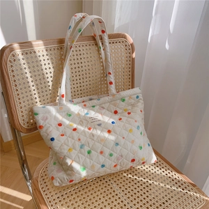 Detail of quilted tote bag with colorful polka dots on a rustic wooden chair