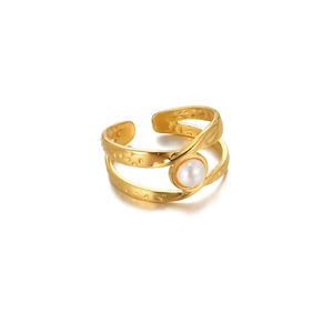Detail of gold open ring featuring hammered texture and a white round pearl