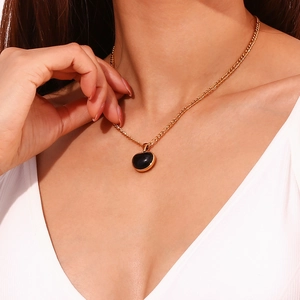 Nahaufnahme einer 18K vergoldeten Halskette mit schwarzem Onyx-Herzanhänger an einem Model