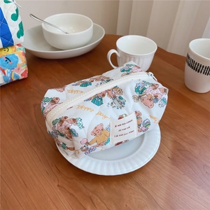Close-up of quilted floral cosmetic bag with cute bear print and zipper detail