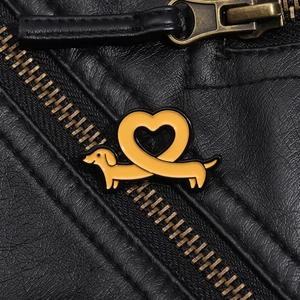 Détail d'une broche teckel en émail jaune en forme de cœur sur une veste en cuir