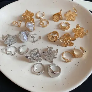Set of gold and silver irregular floral rings and ear cuffs on a ceramic tray