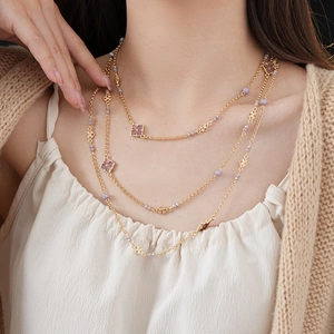 Close-up of a vintage gold multi-layer necklace with flower charms and purple beads