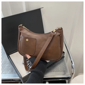 Detail of a brown vintage shoulder bag featuring a small front pocket and gold hardware