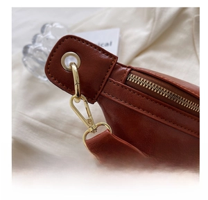 Macro detail of glossy gold hardware hook and premium brown oil wax leather texture