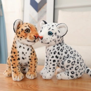 Detail view of realistic plush leopard and snow leopard toys on a wooden table