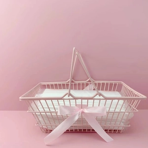 Pink metal mesh storage basket with double handles and decorative ribbon bow detail