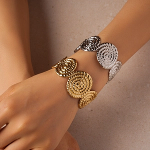 Détail de bracelets joncs superposés or et argent avec motif de relief en spirale tissé