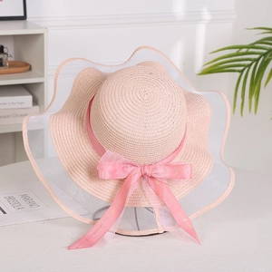 Close-up of pink straw sun hat featuring elegant mesh wide brim and silky bow detail
