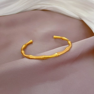 Detailed view of bamboo joint gold plated steel bracelet on elegant satin silk
