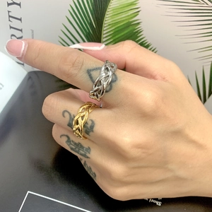 Close-up of gold and silver interwoven chain rings worn on fingers with a lifestyle backdrop