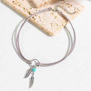 Macro view of bohemian choker featuring silver feather charms and a blue turquoise bead