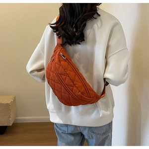 Rear view of model wearing an orange quilted nylon crossbody chest bag with silver zippers