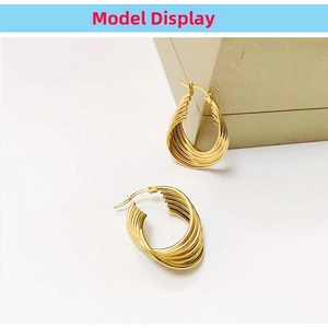 Detailed macro view of 18K gold water wave twisted layered hoop earrings on box