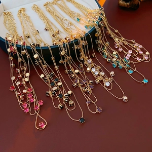 Gros plan de colliers dorés multicouches avec pierres de zircon colorées en boîte