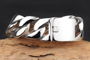 Macro shot of silver titanium steel Cuban link bracelet with flat clasp on wood