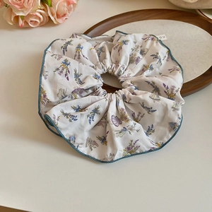 Detailed close-up of a floral fabric scrunchie with lavender, blue flowers, and rabbit motifs