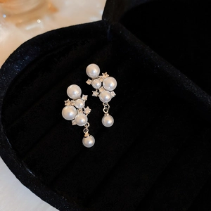 Close-up of stacked white pearl earrings with zircon accents in a black velvet jewelry box