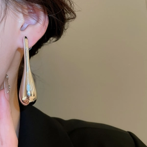 Macro side view of large silver teardrop pendant earring with polished mirror finish